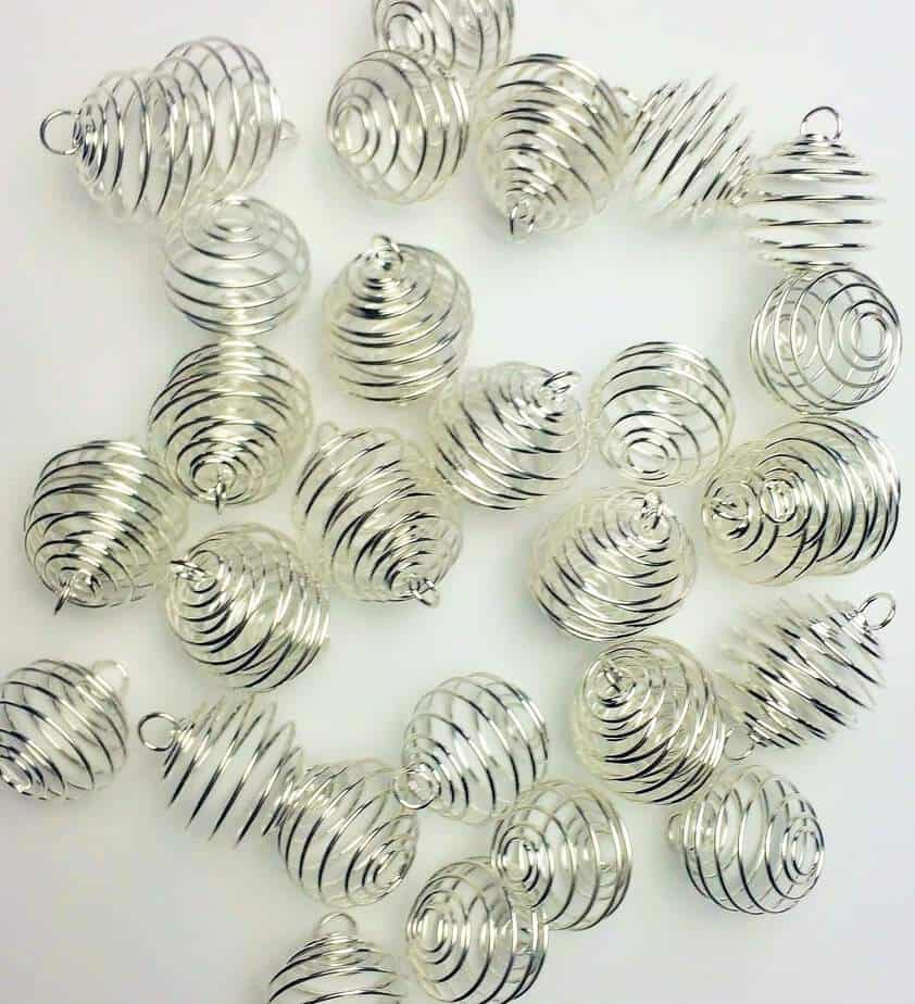 a pile of silver wire cage pendants used to make diffuser jewelry