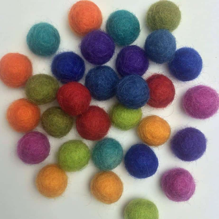 a pile of small colorful wool balls that will be used inside of the wire cage necklace pendants 
