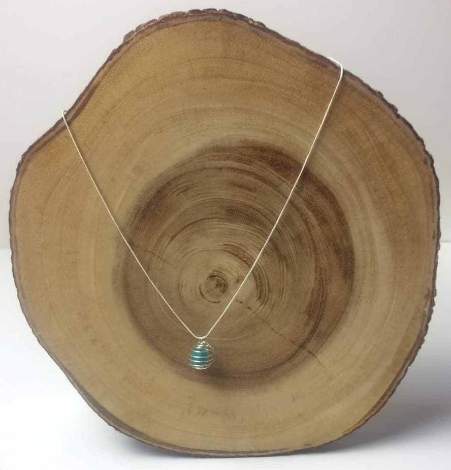essential oil diffuser necklace displayed on slice of cedar tree to show what it would look like on neck