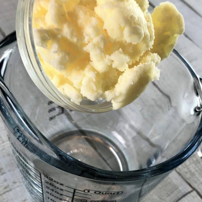 Avocado butter added to clear heat-safe measuring cup, first step making Copycat Lush Ocean Salt scrub recipe made with essential oils
