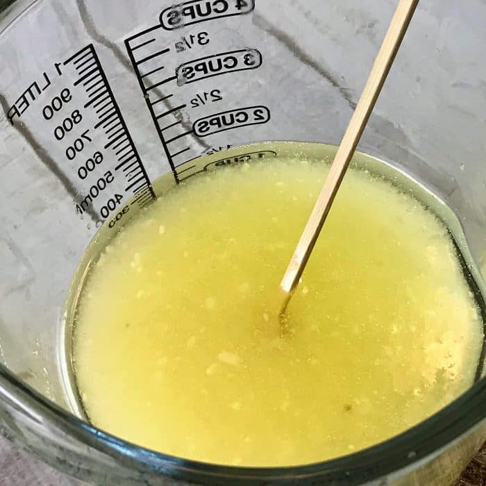 Stirring mixture of salts and melted avocado butter and coconut oil for Copycat Lush Ocean Salt scrub recipe made with essential oils