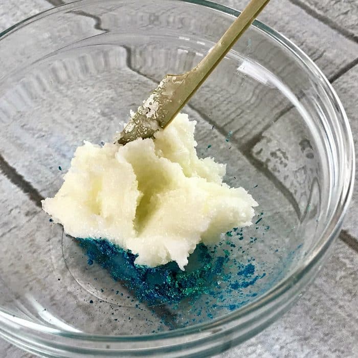 Mixing mica with tablespoon of salt, butter, oil mixture to create ocean blue top layer of Copycat Lush Ocean Salt scrub recipe made with essential oils 