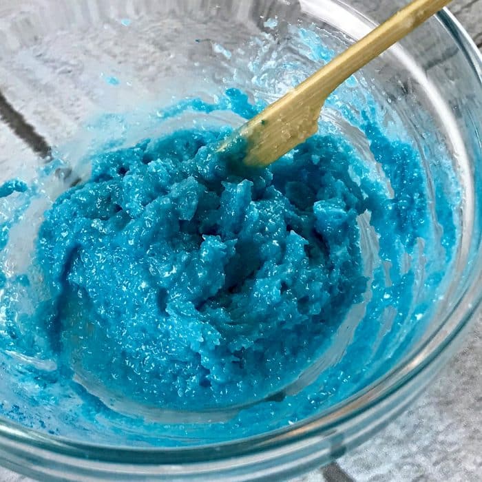 Mixing mica with tablespoon of salt, butter, oil mixture to create ocean blue top layer of Copycat Lush Ocean Salt scrub recipe made with essential oils
