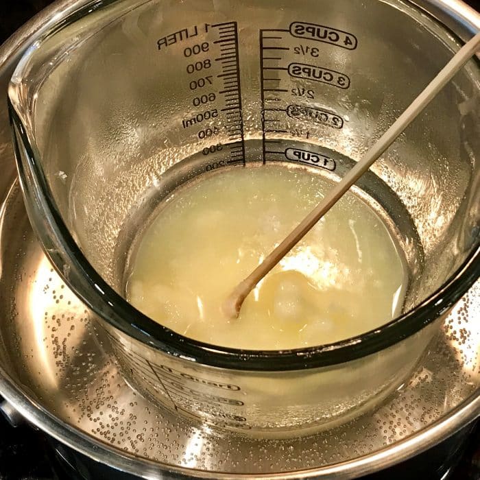 Melted avocado butter and coconut oil in clear heat-safe measuring cup for Copycat Lush Ocean Salt scrub recipe made with essential oils