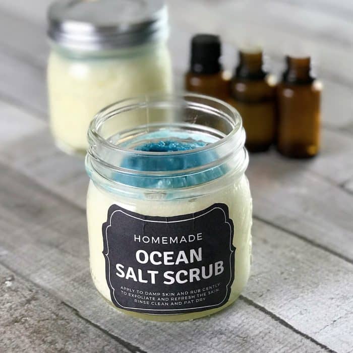 Copycat Lush Ocean Salt scrub recipe made with essential oils in clear jay with custom label with extra scrub and essential oil bottles in background