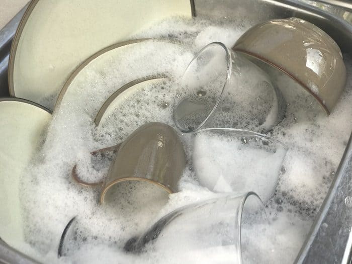 sink full of dishes and lots of bubbles/suds from homemade dish soap