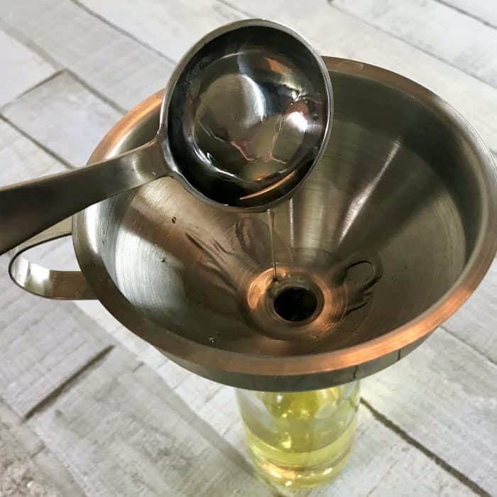 using funnel to add castor oil to natural hair serum for frizz