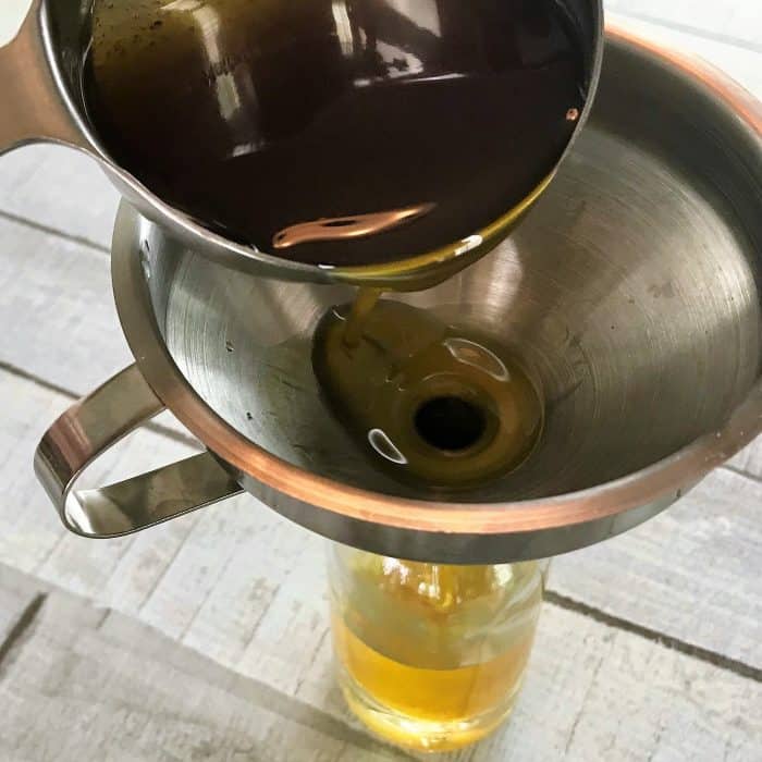 adding flaxseed oil to glass spray bottle via funnel