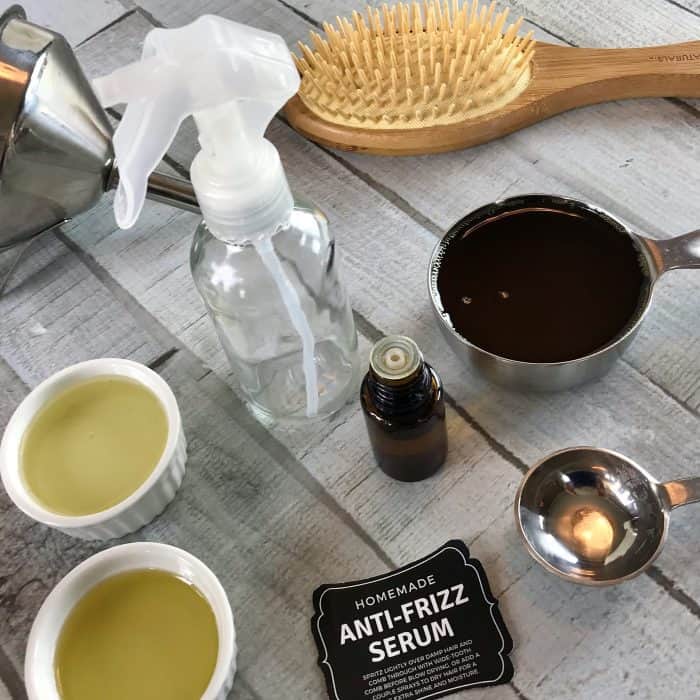 supplies for anti-frizz hair serum -- glass spray bottle, funnel, essential oil, free printable label, measuring cups and measuring spoon with oils