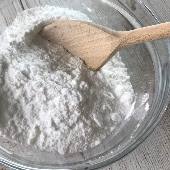 baking soda and borax in glass mixing bowl with wooden spoon