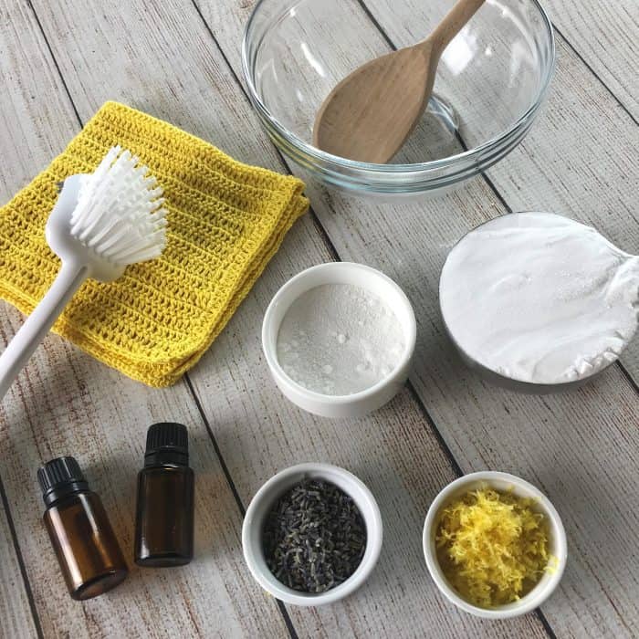 supplies for homemade scouring powder {made with essential oil} -- glass mixing bowl, wooden spoon, two essential oil bottles, baking soda, boarx, lavender buds, lemon peel -- 