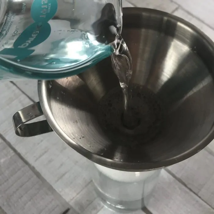 measuring cup adding distilled water to funnel