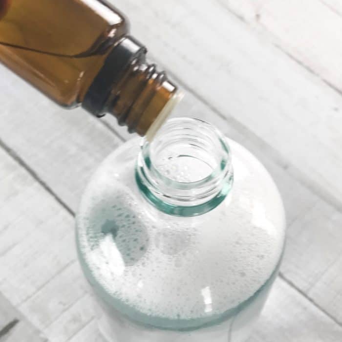 adding lemon essential oil and sweet orange essential oil to kitchen degreaser spray bottle