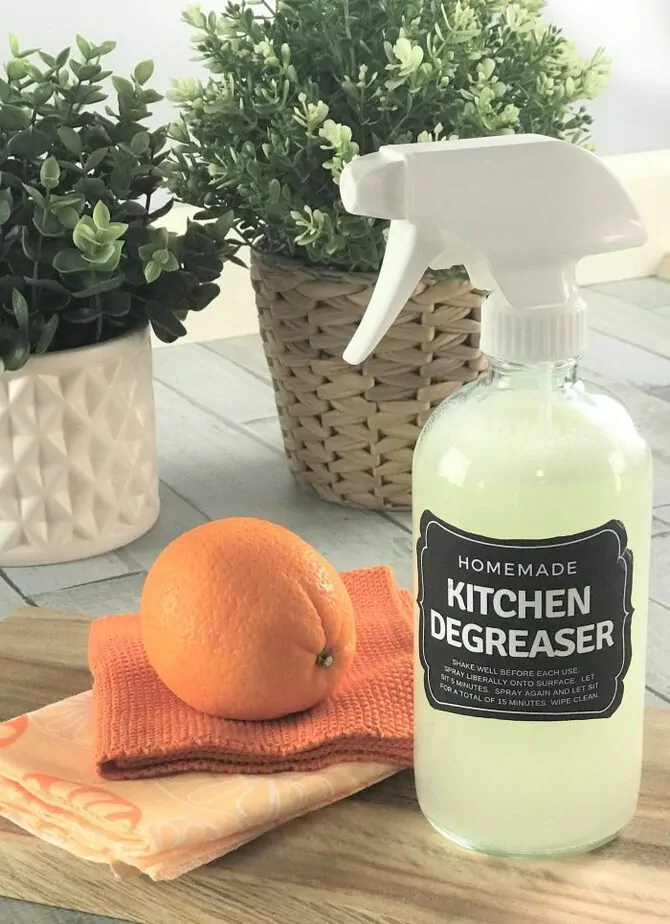 diy citrus degreaser cleaning spray next to orange in front of kitchen houseplants