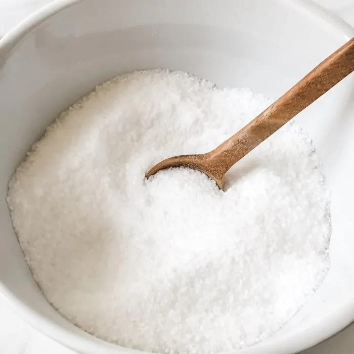 bath salts in white ceramic bowl with wooden spoon