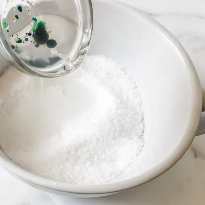 pouring oils and soap colorant into bowl with salts