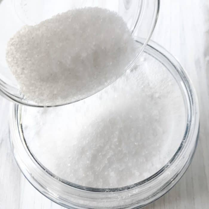 measuring cup pouring Epsom salt into DIY washing powder recipe