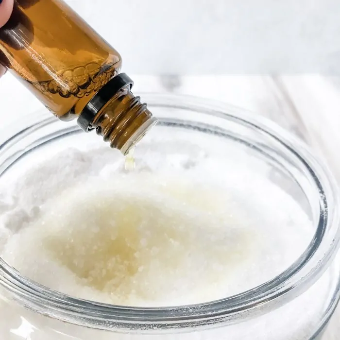 essential oil bottle adding lemon oil to homemade washing powder in jar