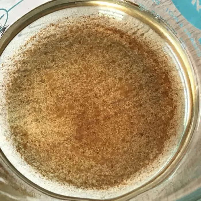 vanilla oleoresin and coconut oil stirred together in glass measuring cup