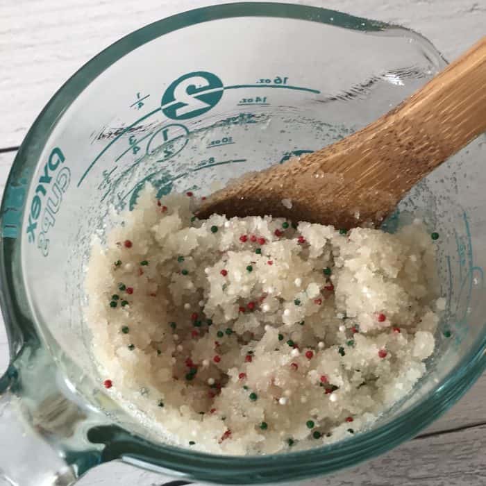 stirring the sugar scrub mixture together with wooden spoon