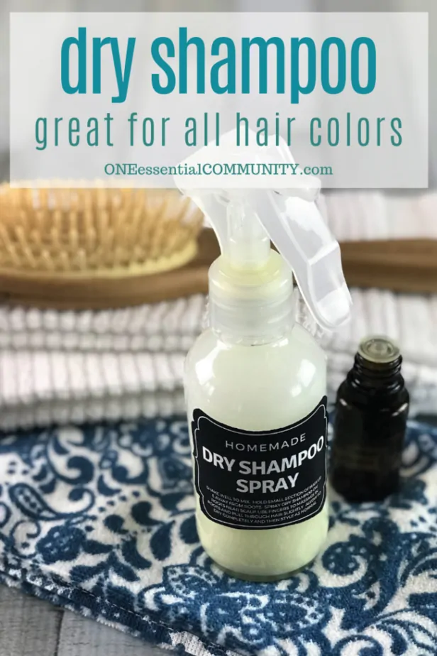 homemade dy shampoo spray in front of hair brush and next to essential oil bottle