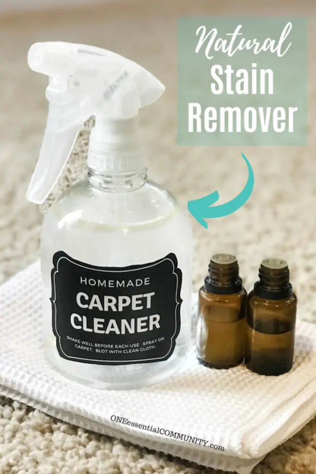 homemade carpet cleaner spray bottle, lemon essential oil, and tea tree essential oil on white cloth with words natural stain remover