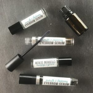 several homemade eyebrow growth serum tubes on table with essential oil bottle