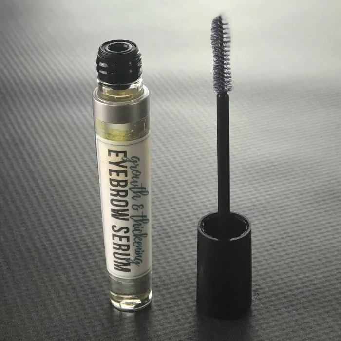 DIY eyebrow serum in mascara tube with applicator wand beside it
