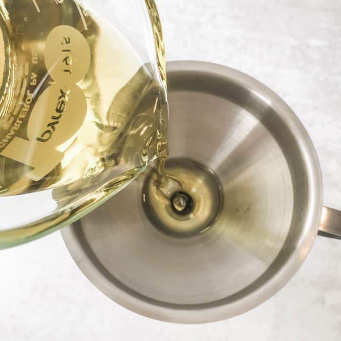 pouring olive oil into funnel for use in homemade furniture polish
