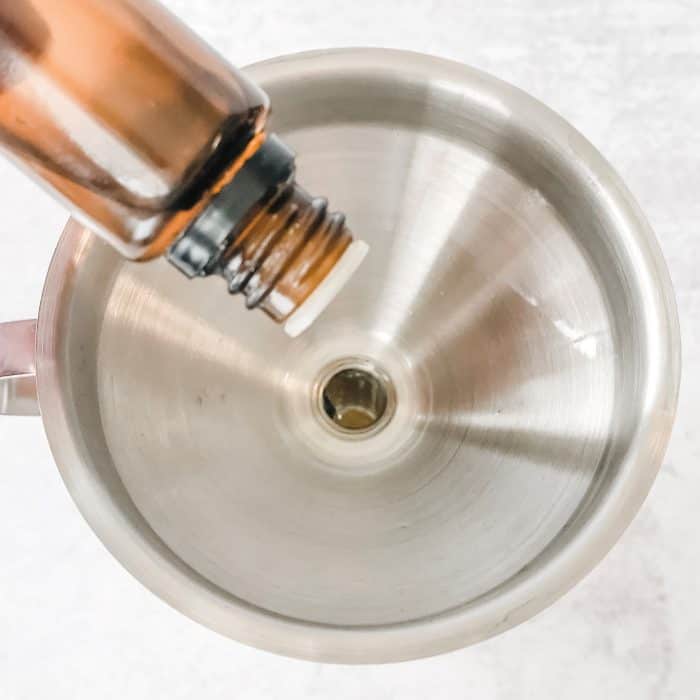 adding drops of sweet orange essential oil into bottle through a funnel