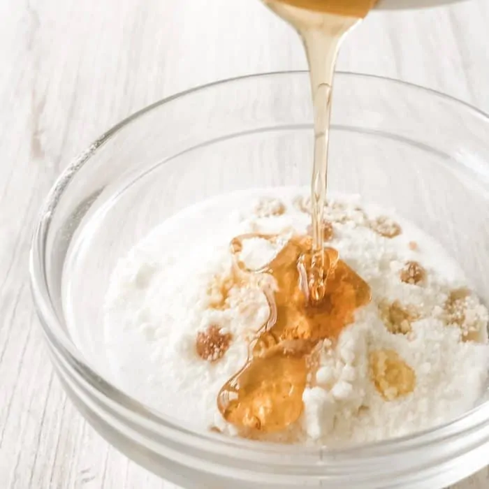 adding honey to super fine sugar, ground white chocolate, vanilla extract, and tangerine essential oil