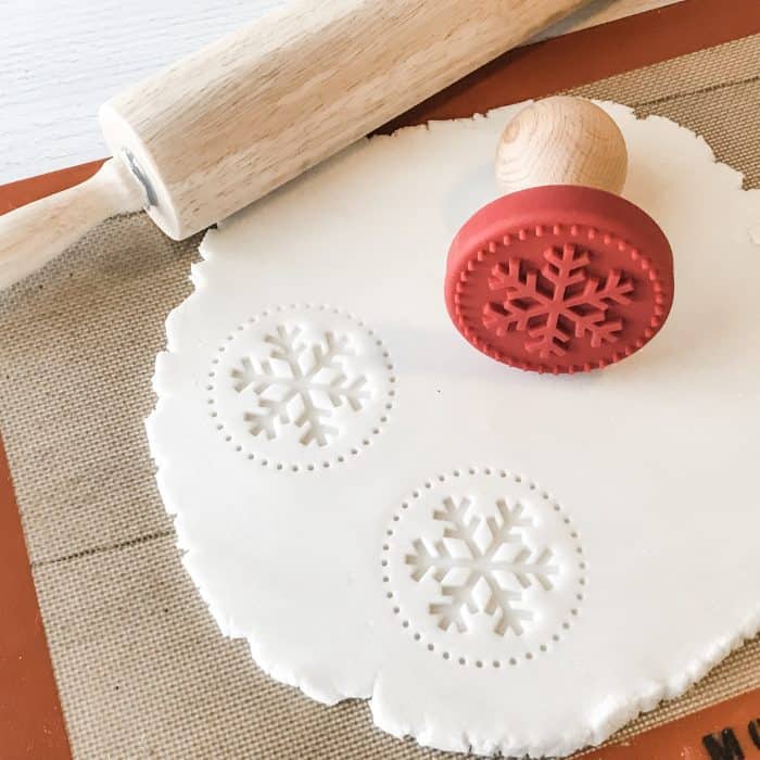 snowflake cookie stamps into salt dough scented with essential oils, on silpat next to rolling pin