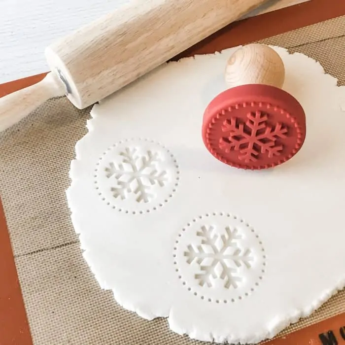 snowflake cookie stamps into salt dough scented with essential oils, on silpat next to rolling pin