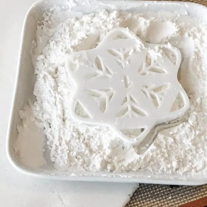 snowflake cookie cutter dipped in bowl of flour