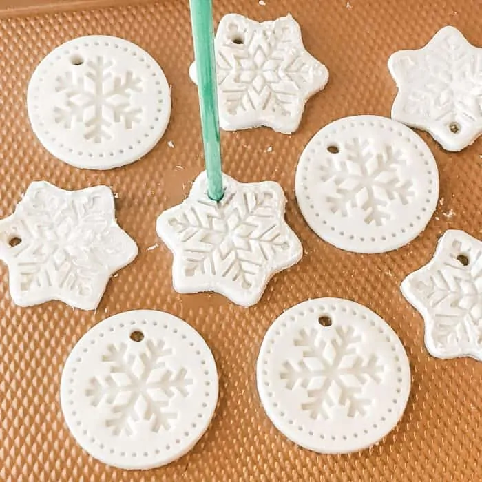 homemade salt dough ornaments scented with essential oils in snowflake shapes, using straw to cut a hole through each one for hanging