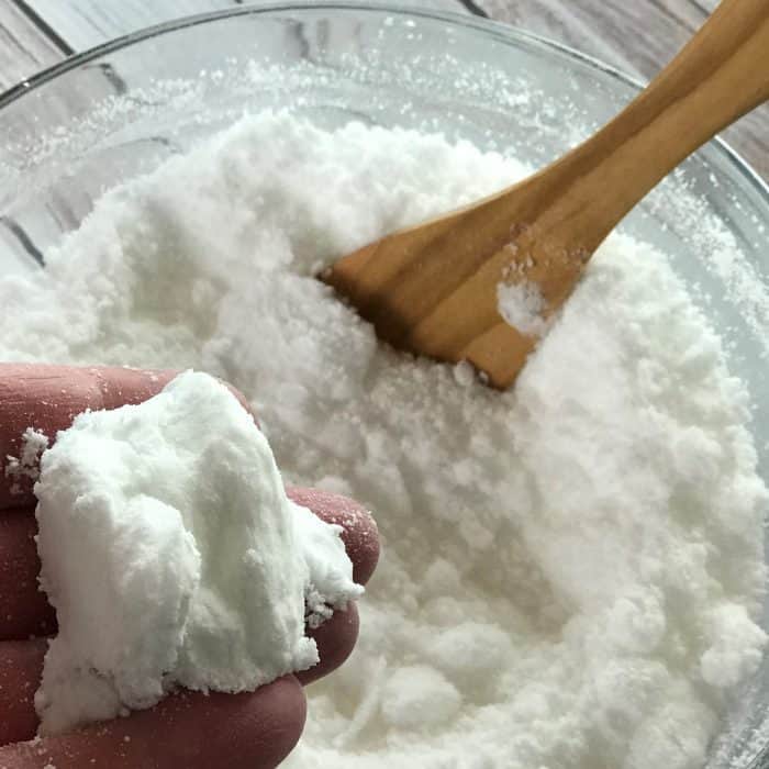 picking up part of facial steamer tea tree tab mixture with hand to show clumping together of witch hazel tea tree essential oil baking soda citric acid