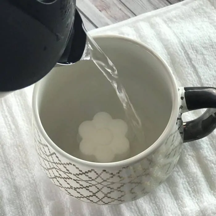 pouring hot water into mug with flower shaped tea tree essential oil facial steamer tab to activate steamer