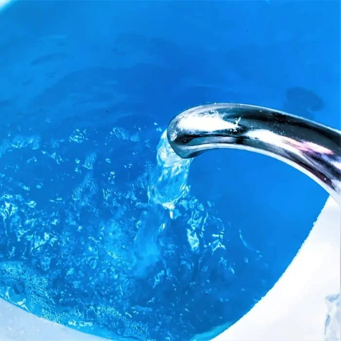 running bath water faucet into blue water