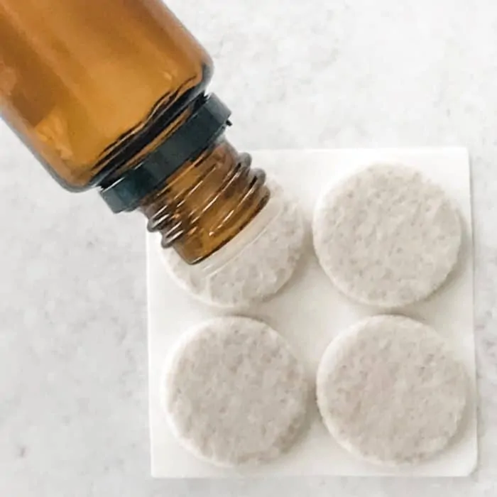 adding drops of essential oil from essential oil bottle to felt pads