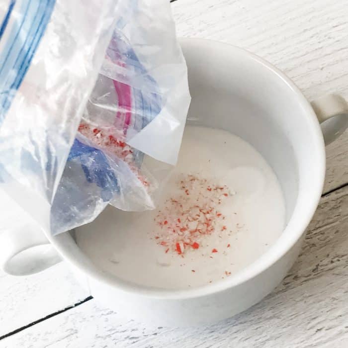 adding smashed candy cane pieces to bowl with sugar for use in peppermint candy cane lip scrub with essential oils