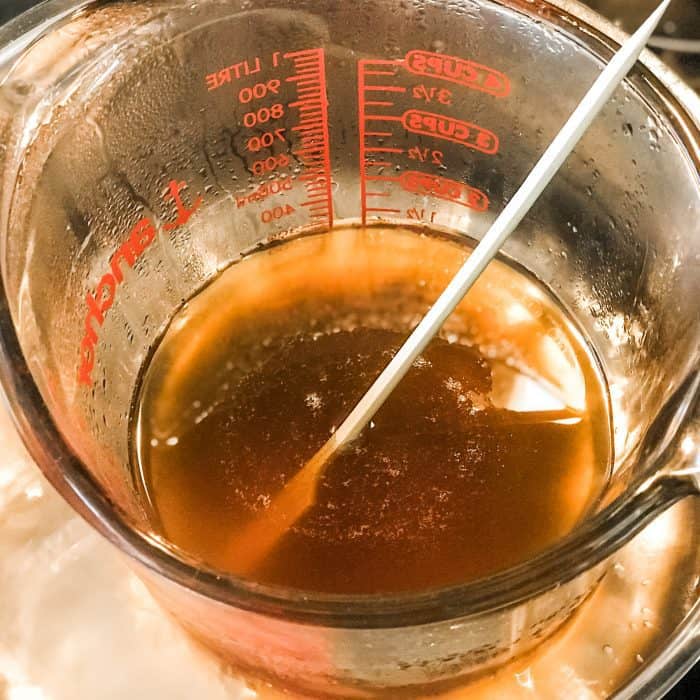 melted cocoa butter and shea butter in glass jar on top of saucepan with water, for use in Lush Buffy Bar