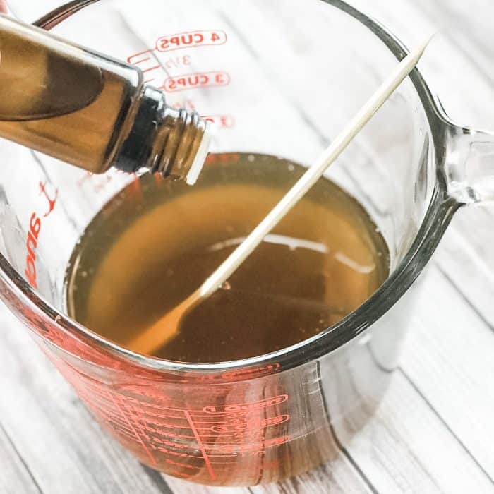 adding lemon and lavender essential oils to melted cocoa butter and shea butter, making DIY Lush Buffy Bar with essential oils