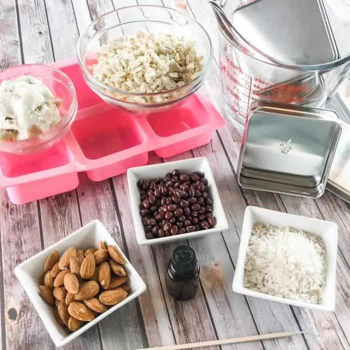 DIY Lush Buffy Bars ingredients and tools - lemon and lavender essential oils, cocoa butter and shea butter, almonds, rice, adzuki beans, silicone molds, Lush tins, measuring cups and bowls