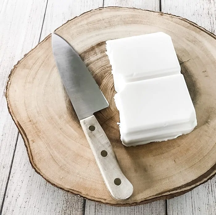 block of goat's milk melt & pour soap on wooden block, next to chef's knife with wooden handle