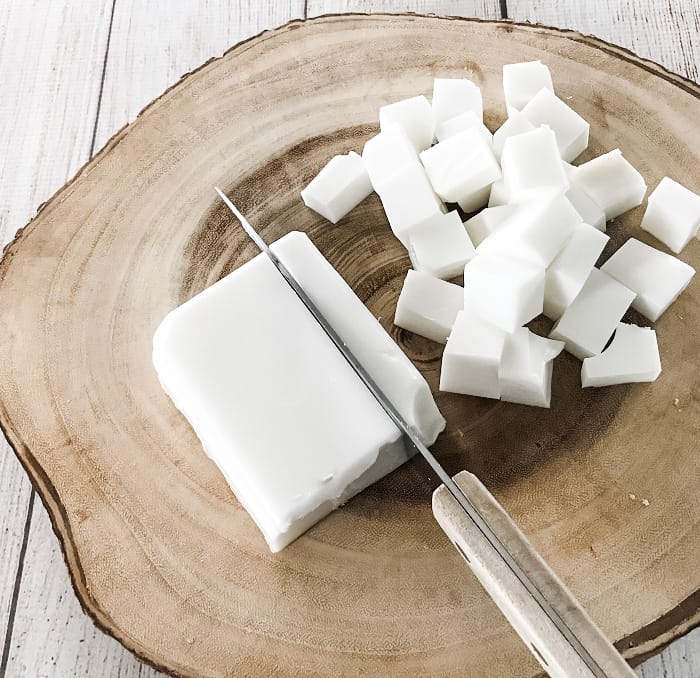 cutting block of goat's milk melt & pour soap into half-inch cubes step in making DIY clay facial soap with essential oils