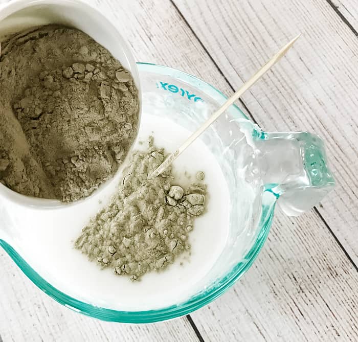 adding bentonite clay to melted goat's milk melt and pour soap with essential oil wooden skewer ready to stir making DIY clay facial soap One Essential Community