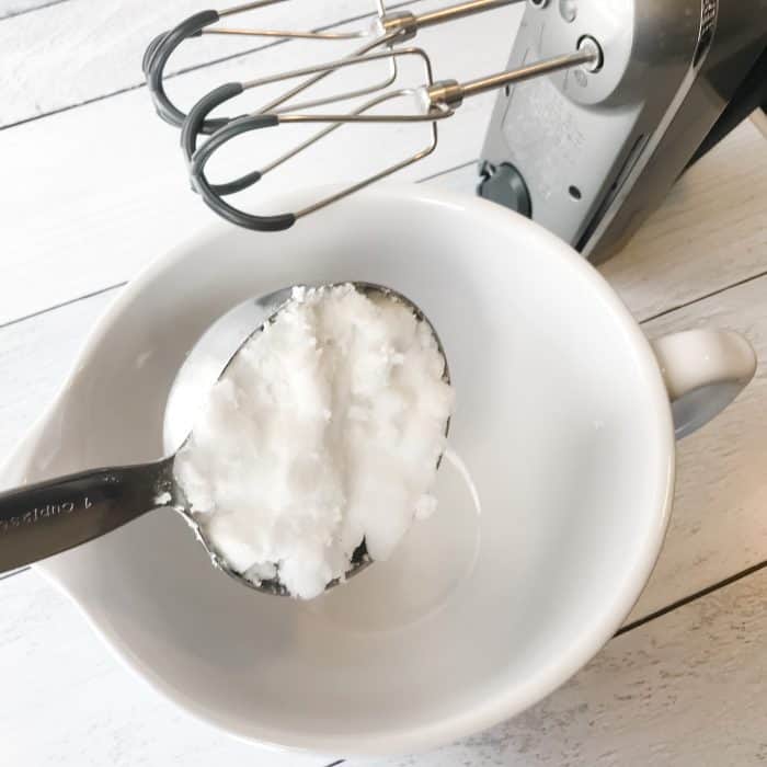 essential oil joint pain cream first step coconut oil in measuring spoon ready to add to bowl with mixer ready