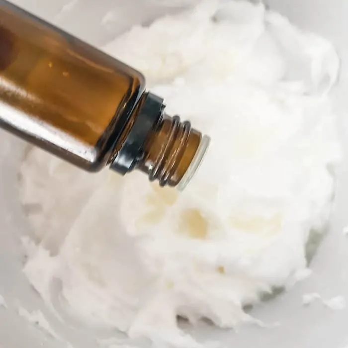 adding essential oil to whipped coconut oil cream while making Joyful Joints cream to treat aching hands, knuckles, shoulders, knees, feet