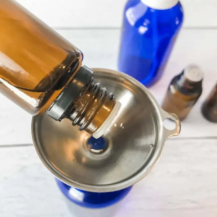 adding essential oil through funnel to spray bottle while making Winter Blues body spray with essential oils