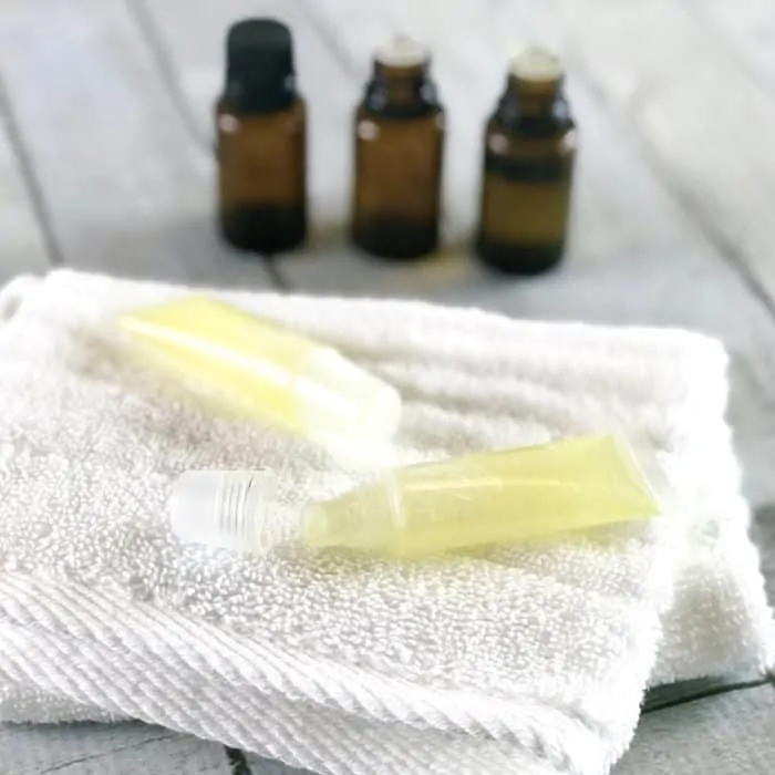 DIY natural essential oil acne gel in silicone tube on towel with essential oil bottles in background natural acne treatment for zits and other blemishes
